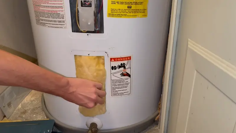 Insulation pulled back from the lower element access panel of an electric water heater